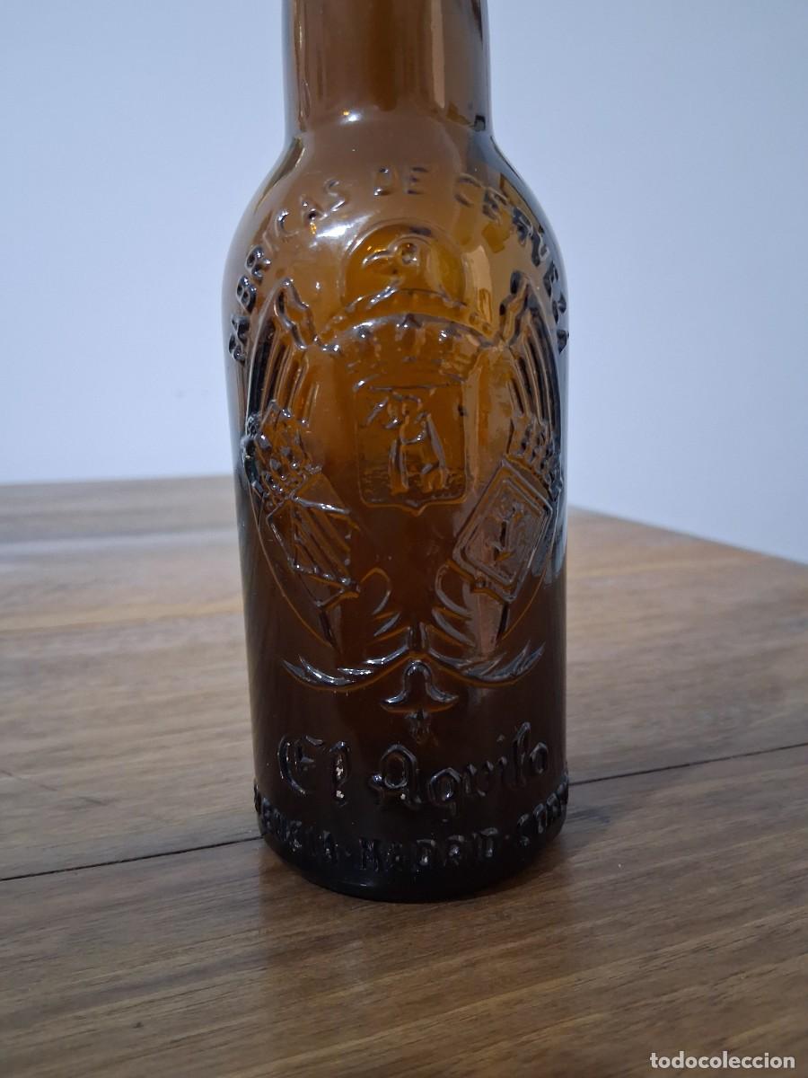 Coleccionismo de cervezas: Botella en relieve cerveza El aguila tercio cristal marron ambar Valencia Madrid C&oacute;rdoba