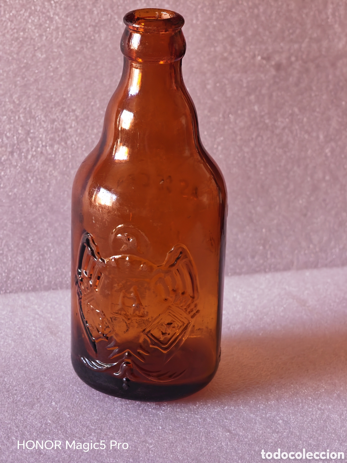 Coleccionismo de cervezas: Antigua botella de cerveza de un tercio el aguila escudo y letras en relieve