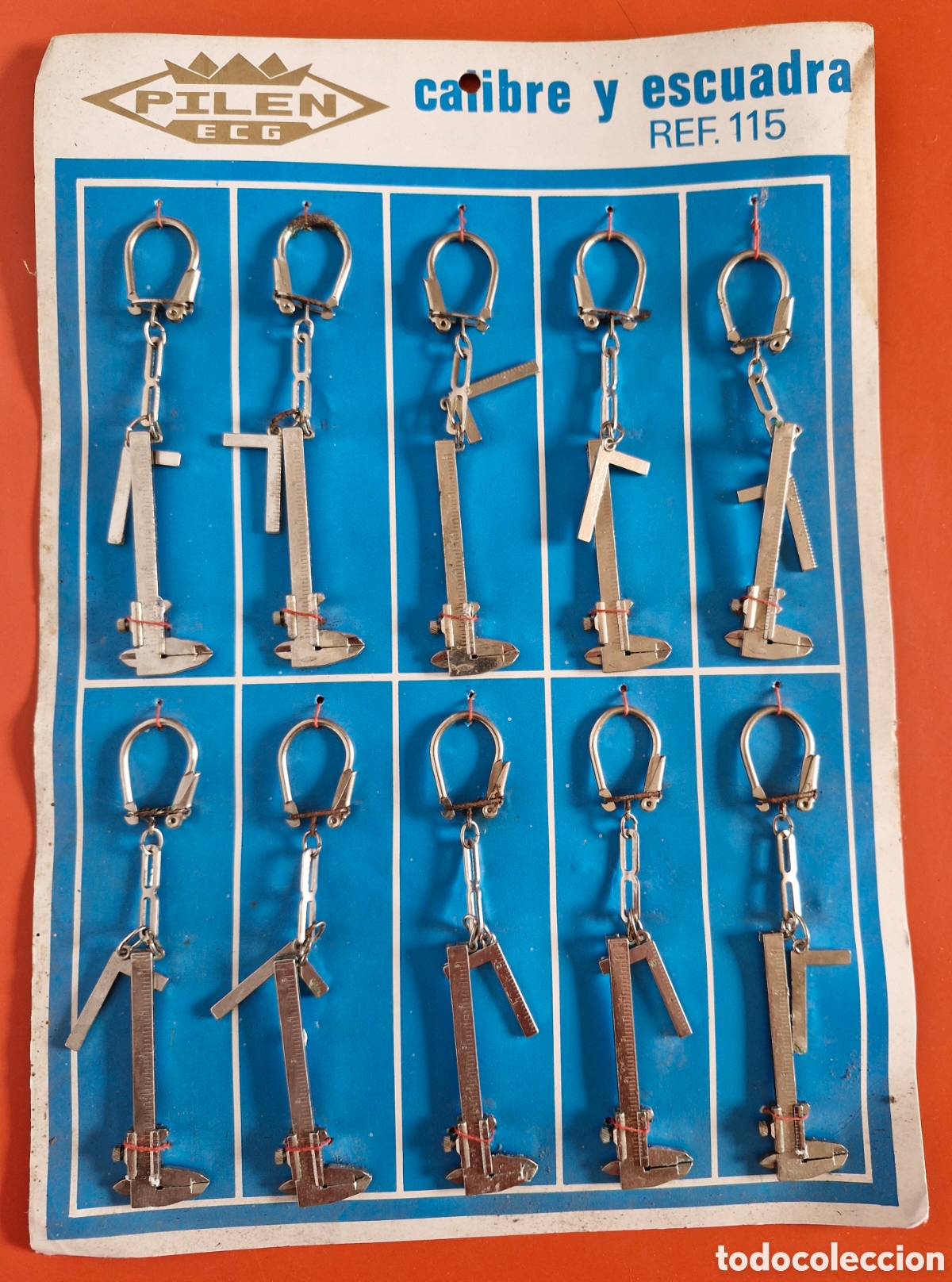 Collection of Keychains: EXPOSITOR DE 10 LLAVEROS CALIBRE Y ESCUADRA MET&Aacute;LICOS.PILEN 80'S.NUEVOS.
