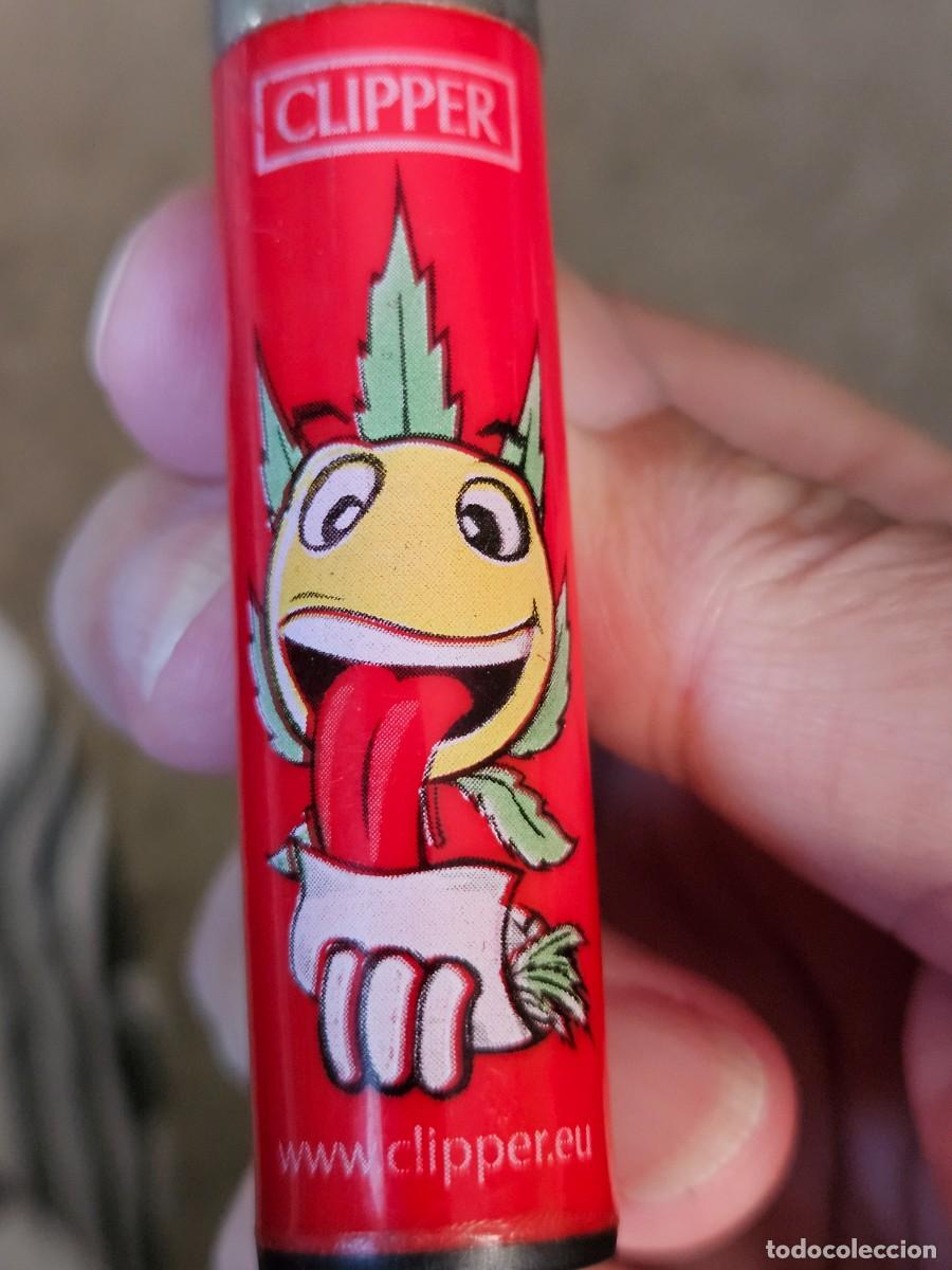 Mecheros: Mechero/ Encendedor Clipper Emoji Con Hoja De Marihuana Liando Un Porro Sobre Fondo Rojo.