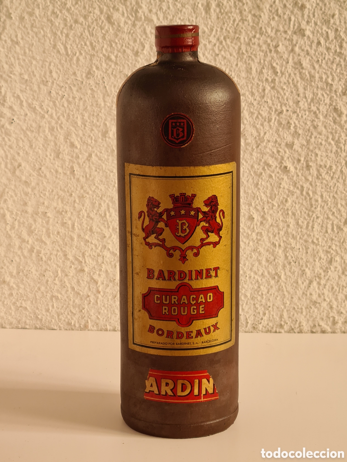 Sammlung von Weinen und Lik&ouml;ren: Botella de Cer&aacute;mica con Asa Cura&ccedil;ao Rouge Bordeaux Bardinet 1 L. - Licor Aguardiente
