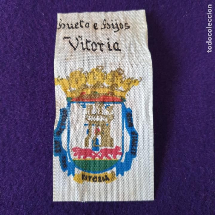 Coleccionismo: DISTINTIVO DE TELA CON EL ESCUDO DE VITORIA. DE CHOCOLATES HUETO E HIJOS. VITORIA