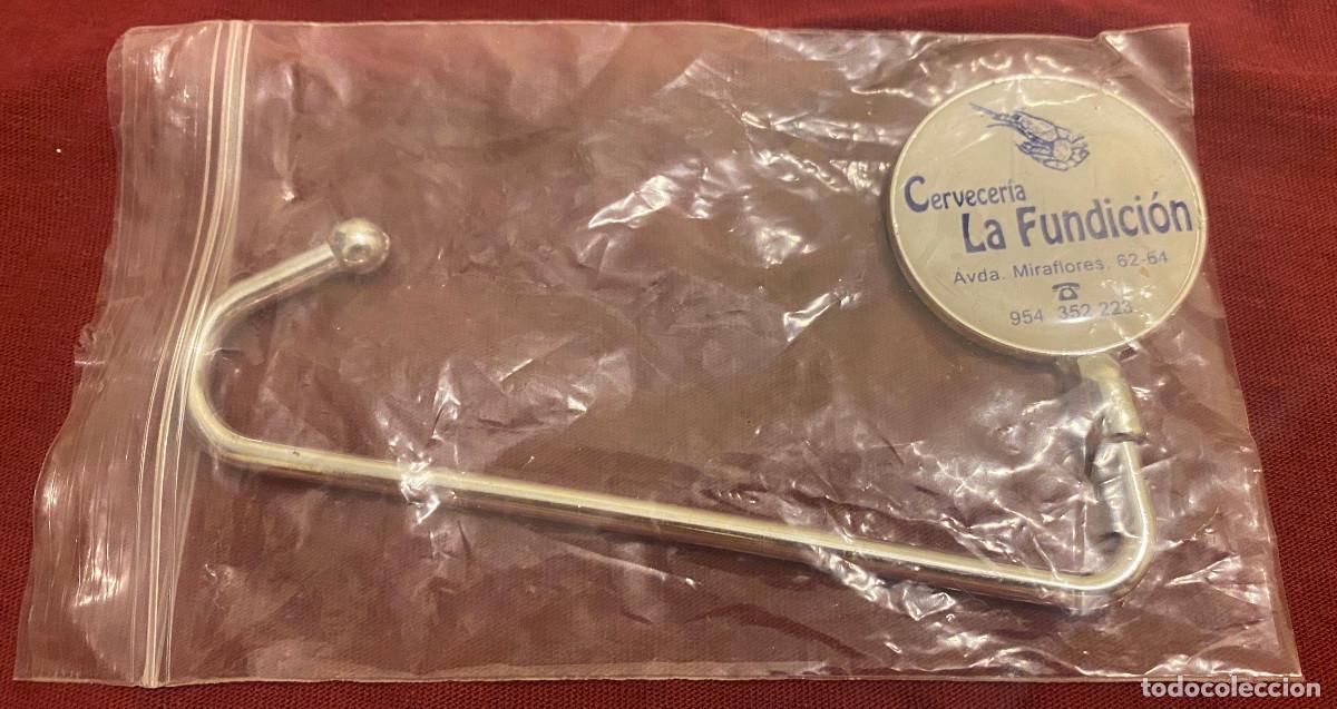 Coleccionismo: Accesorio o gancho para colgar bolsos. Publicitario de cervecer&iacute;a de Sevilla. Vintage a&ntilde;os 90. Nuevo