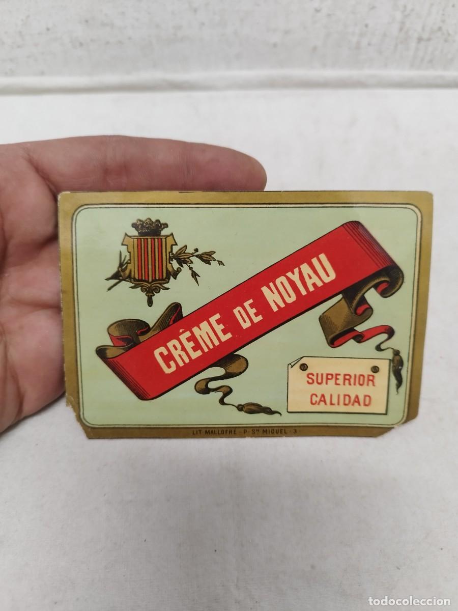 Etiquetas antiguas: Antigua etiqueta de Cr&egrave;me de Noyau&rdquo; con una cinta roja y un sello de &rdquo;Superior Calidad&rdquo;.