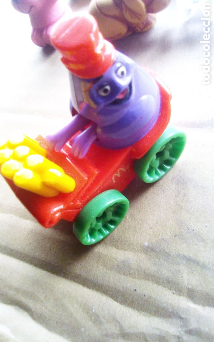 Figuras de Goma y PVC: Juguete cochecito con monstruo morado tocando el &oacute;rgano. &copy; 1989 McDonald's Corp. Mide 6 x 6 cm.