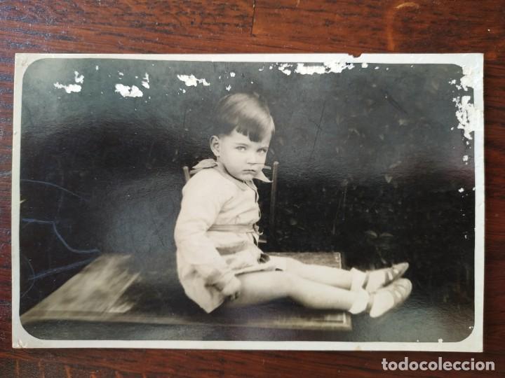 Fotografia antiga: Retrato de ni&ntilde;o con bata de escuela sentado encima de mesa.de principios del siglo XX