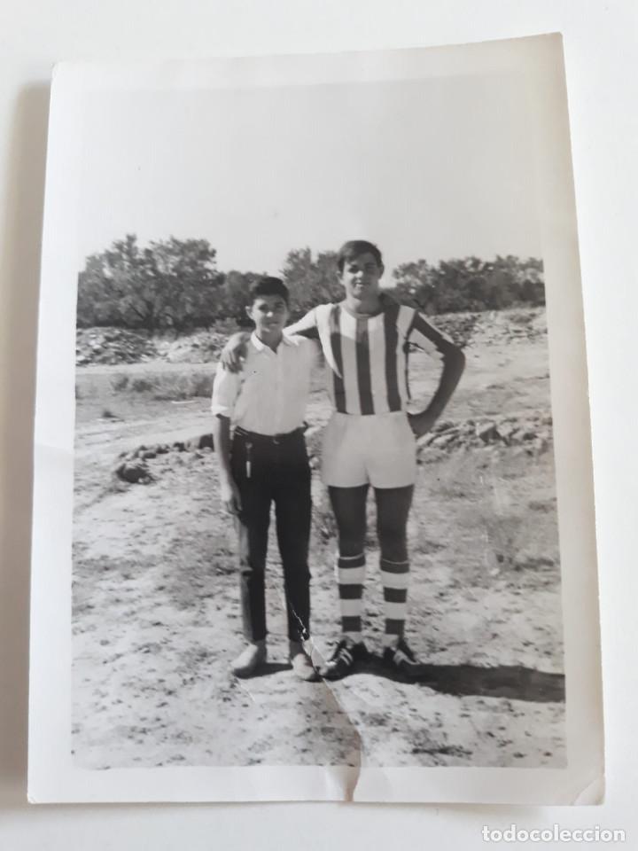 Fotografia antiga: Joven con equipaci&oacute;n de futbol acompa&ntilde;ado de otro joven