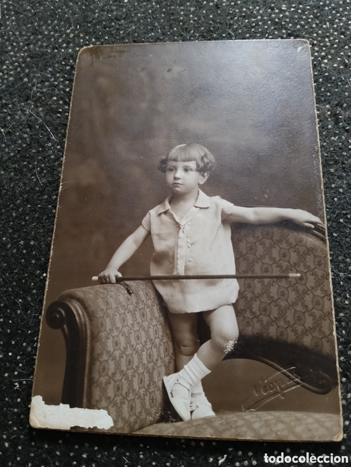 Fotograf&iacute;a antigua: Fotograf&iacute;a de un ni&ntilde;o en un div&aacute;n con un bast&oacute;n en la mano 1910-30