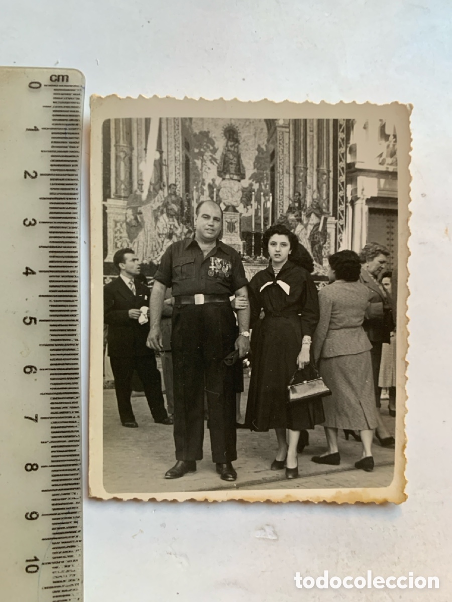 Alte Fotografie: FOTO. FALANGISTA MUESTRA SUS CONDECORACIONES CON SU MUJER ANTE EL TAPIZ DE LA VIRGEN. M. PERIS, FOT.