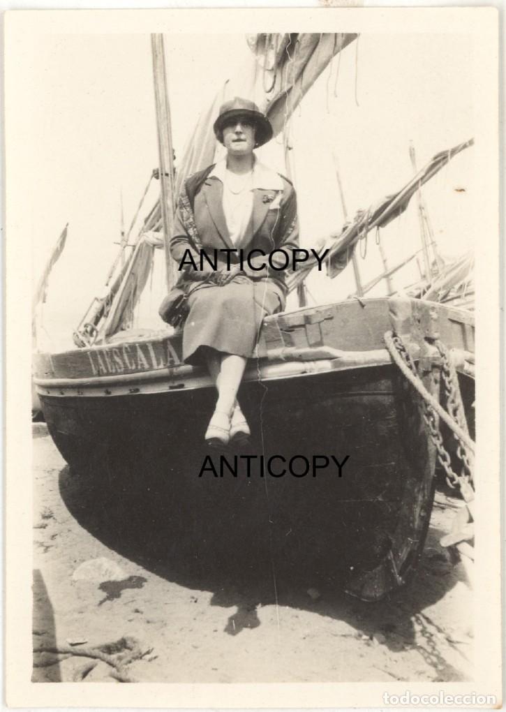 Fotograf&iacute;a antigua: Fotograf&iacute;a. Mujer sentada sobre barco de pesca. Nombre del barco: La Escala. Lugar desconocido.