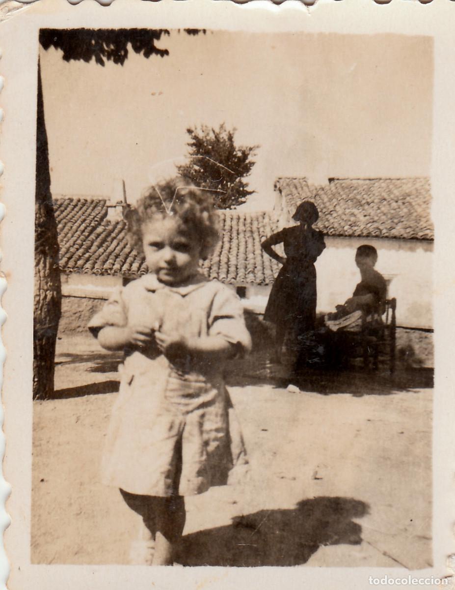 Fotograf&iacute;a antigua: Ni&ntilde;a delante de los tejados de unas casas bajas. A fondo mujeres charlando. A&ntilde;os40. oc