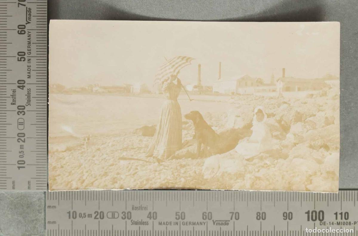 Fotografia antiga: FOTOGRAFIA. Mujer con sombrilla y perro en la playa. AL FONDO FABRICAS. ESPA&Ntilde;A HACIA 1920