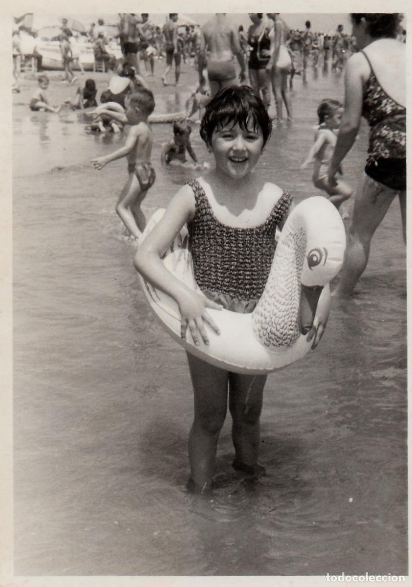 Fotograf&iacute;a antigua: Las felices vacaciones. Ni&ntilde;a con flotador de cisne. Playa llena de ba&ntilde;istas. Tebar, Val&egrave;ncia 60s sv