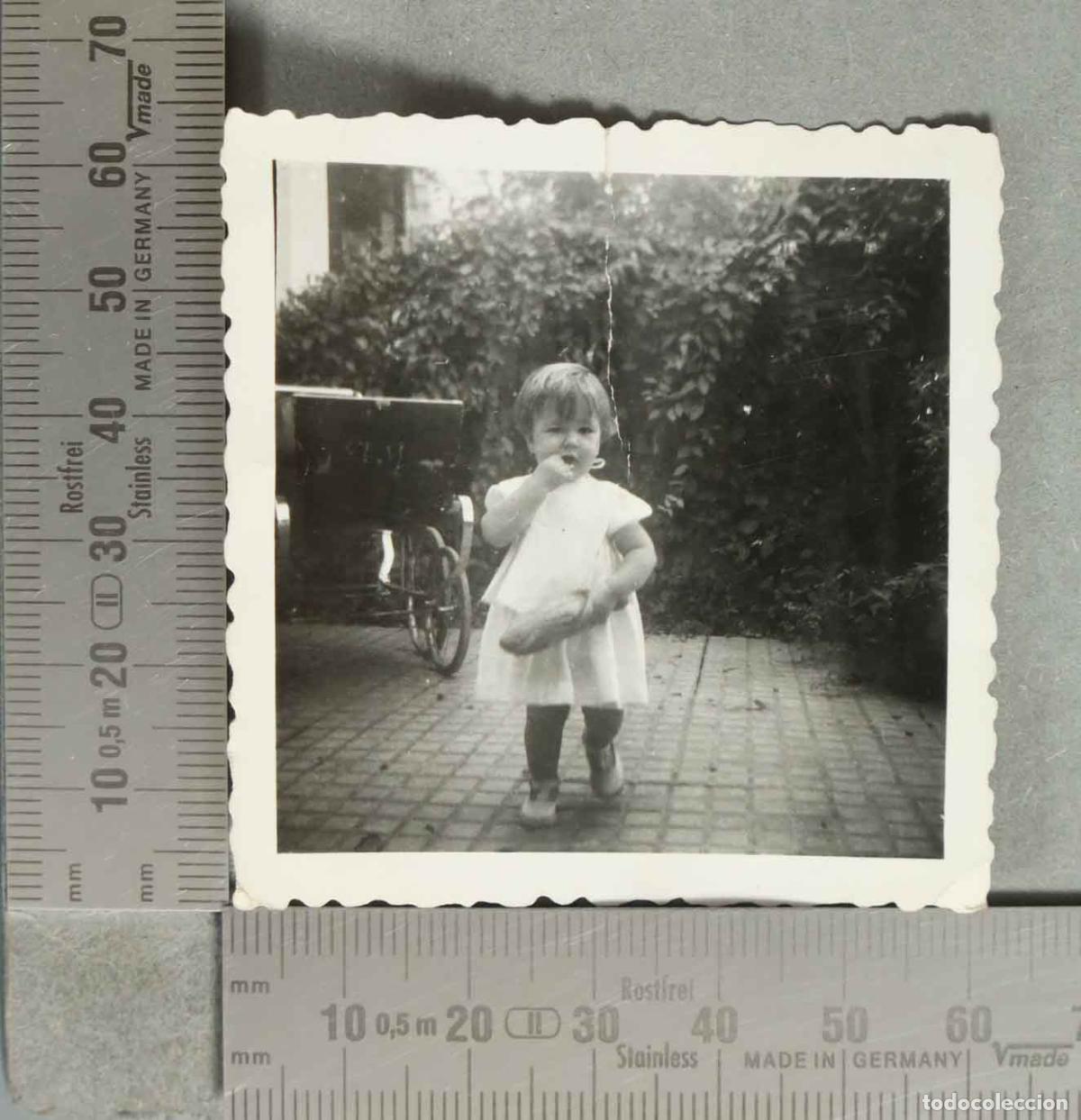Fotografia antica: FOTOGRAFIA. Ni&ntilde;a con vestido blanco comiendo pan junto a cochecito hacia 1940