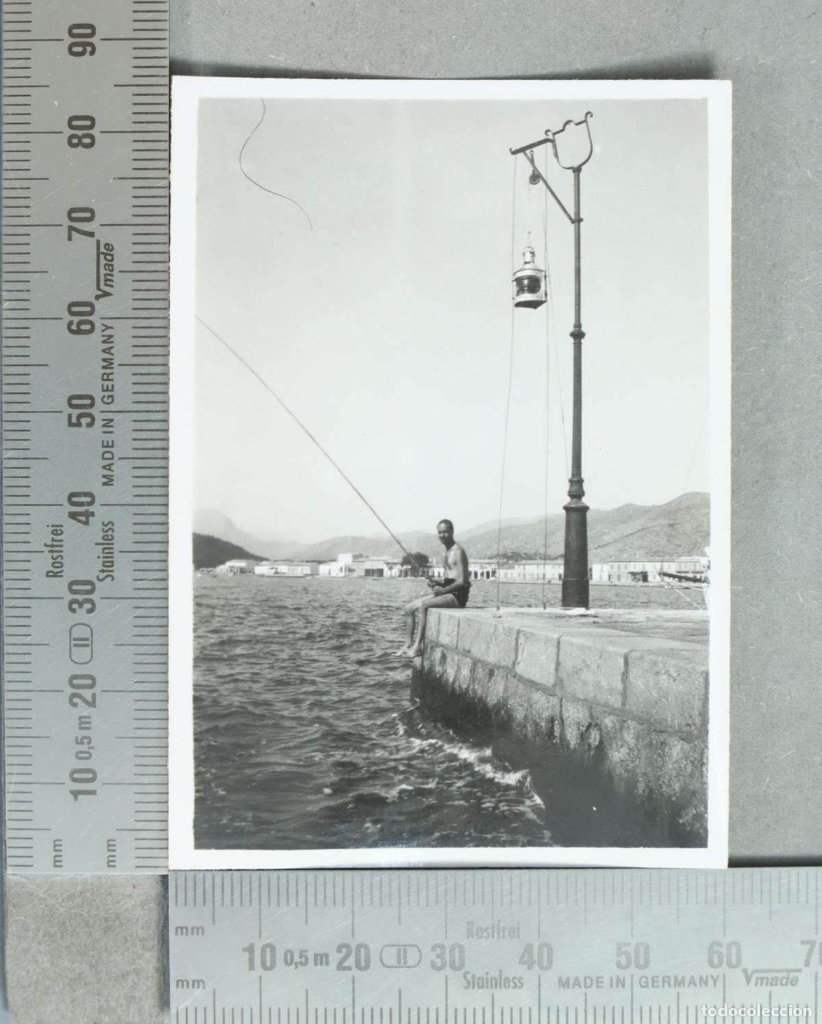 Fotograf&iacute;a antigua: FOTOGRAFIA. Hombre pescando en un muelle BAJO FAROL NAUTICO hacia 1930