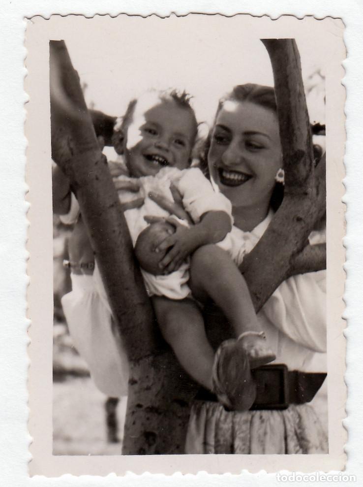 Fotograf&iacute;a antigua: Mam&aacute; feliz subiendo a un &aacute;rbol a su beb&eacute;. A&ntilde;os 50 bm