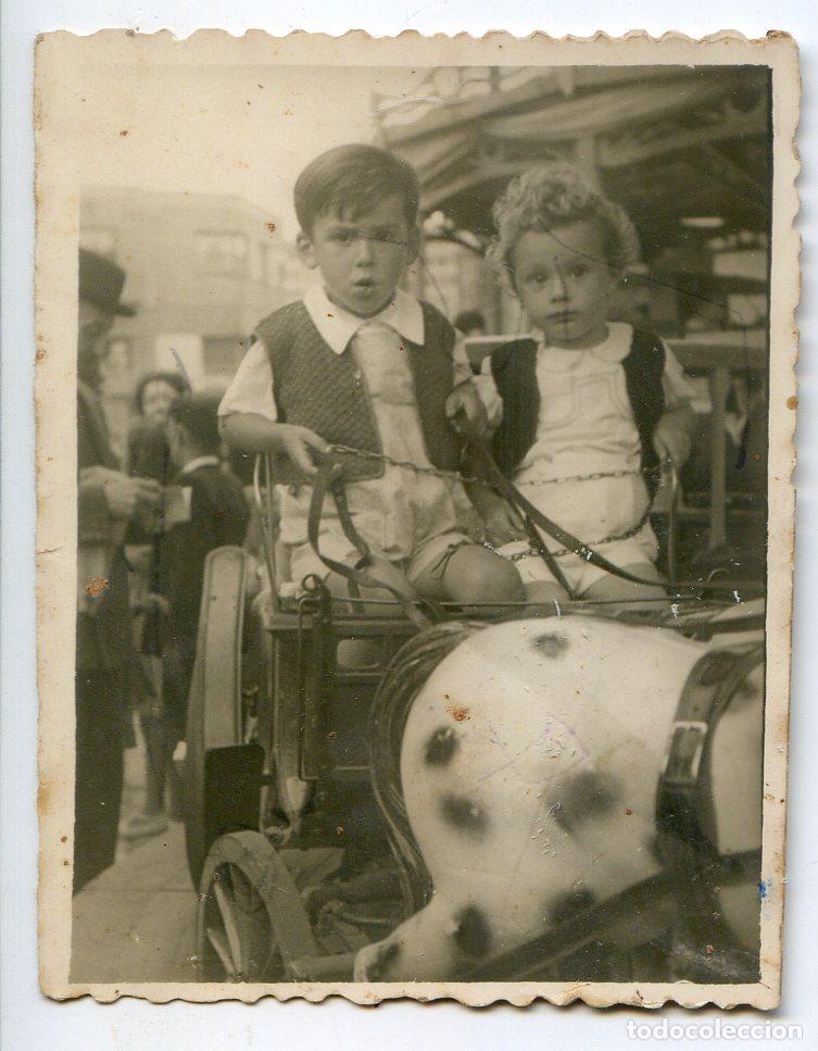 Fotograf&iacute;a antigua: Dos ni&ntilde;os en tiovivo de feria, sin referencia de fot&oacute;grafo ni lugar 6x7,5 cm