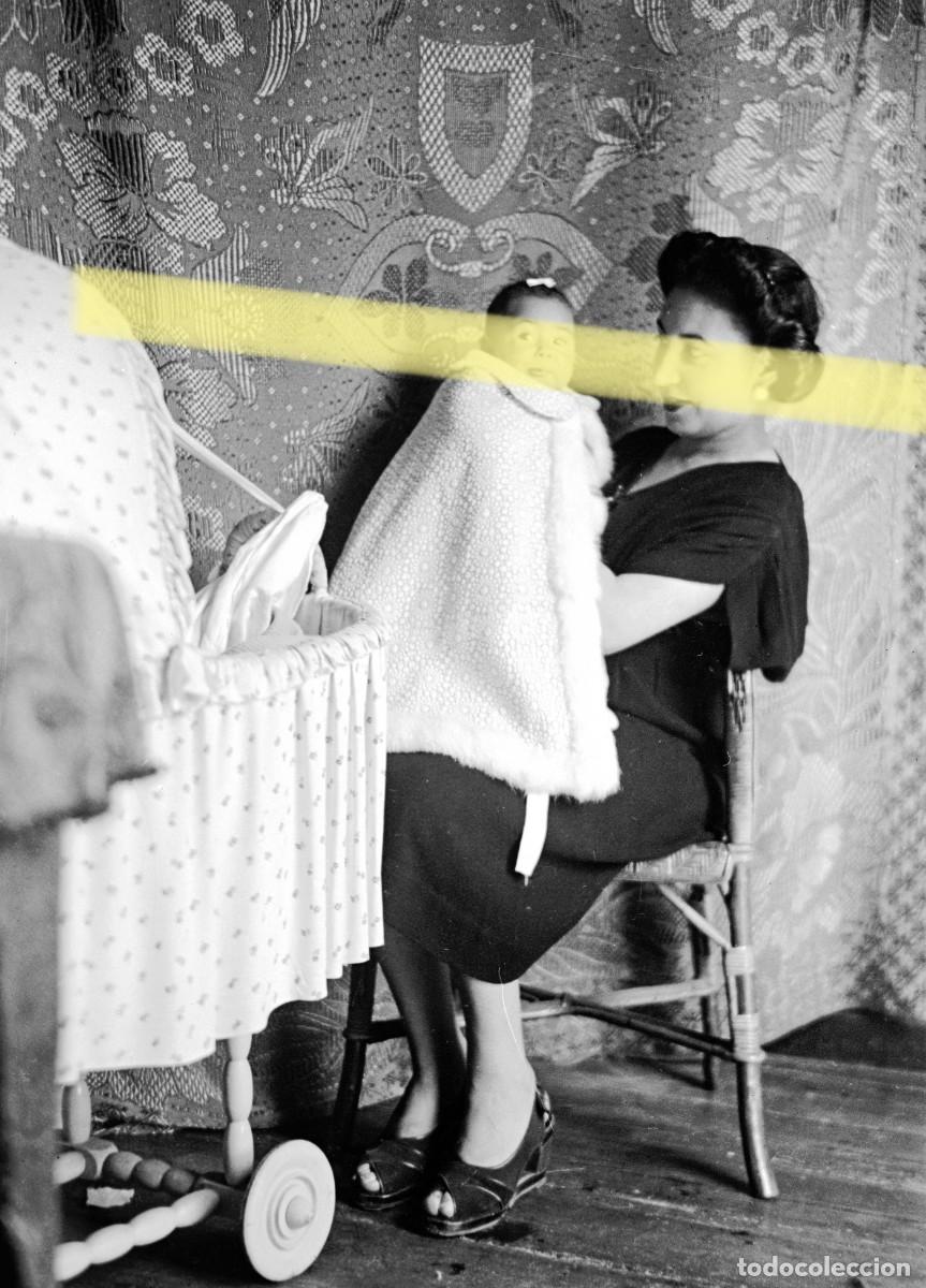 Fotograf&iacute;a antigua: Antiguo negativo de fotograf&iacute;a. Mujer sosteniendo a un beb&eacute; junto a una cuna. A&ntilde;os 40