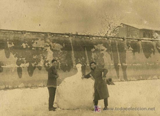 Fotografia antiga: NIEVE. Dos j&oacute;venes haciendo un monigote de nieve delante de un muro. Circa 1930. Lugar desconocido