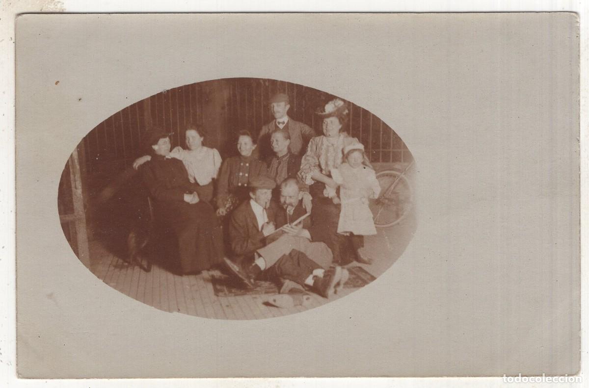 Fotograf&iacute;a antigua: Tarjeta foto: Familia elegante con dos hombres haciendo payasadas en la calle (c. 1910)