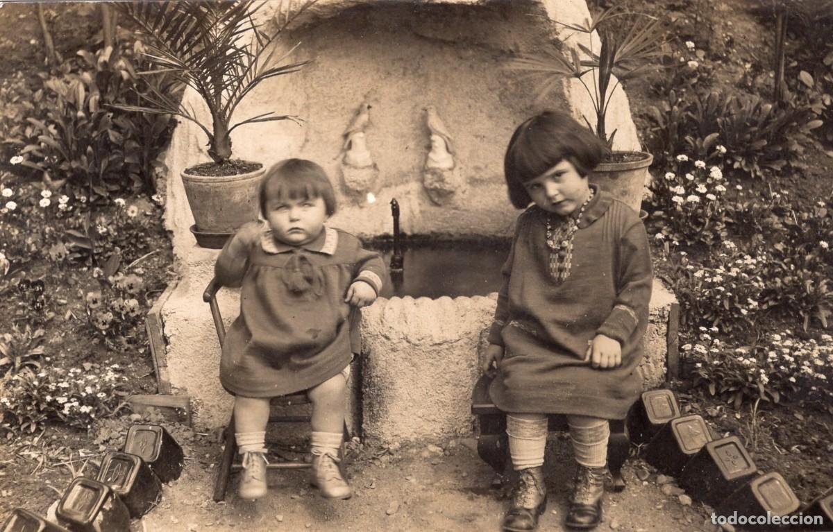 Fotograf&iacute;a antigua: Tarjeta foto: Dos ni&ntilde;as peque&ntilde;as sentadas ante una fuente en el jard&iacute;n (c. 1920)