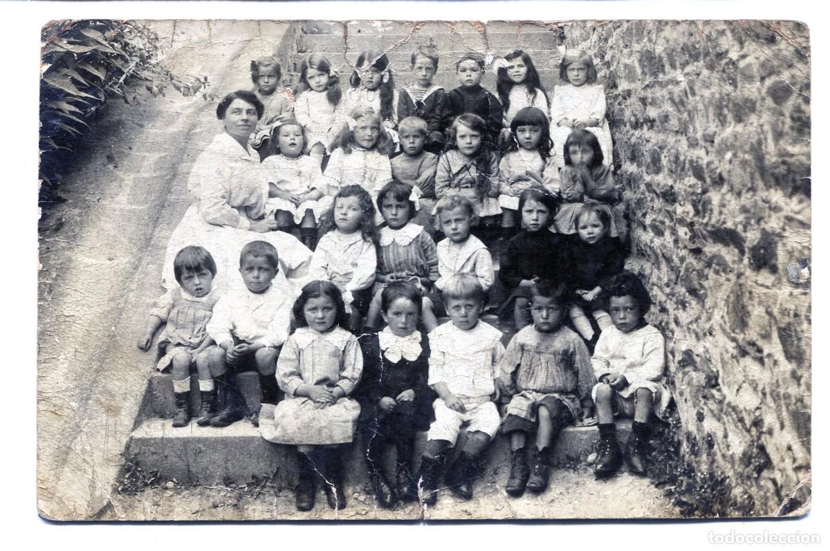 Fotograf&iacute;a antigua: Foto tarjeta. Clase mixta de ni&ntilde;os peque&ntilde;os con su maestra sentados en las escaleras, hacia 1910
