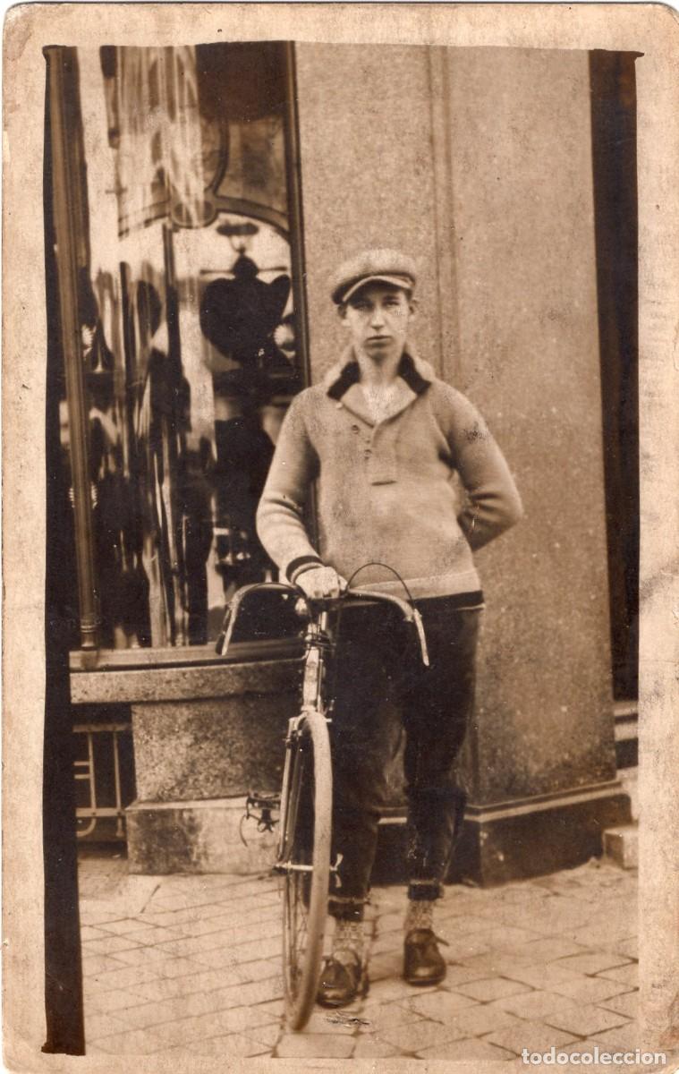 Fotograf&iacute;a antigua: Tarjeta fotogr&aacute;fica de un hombre con su bicicleta en las calles de una ciudad hacia 1930