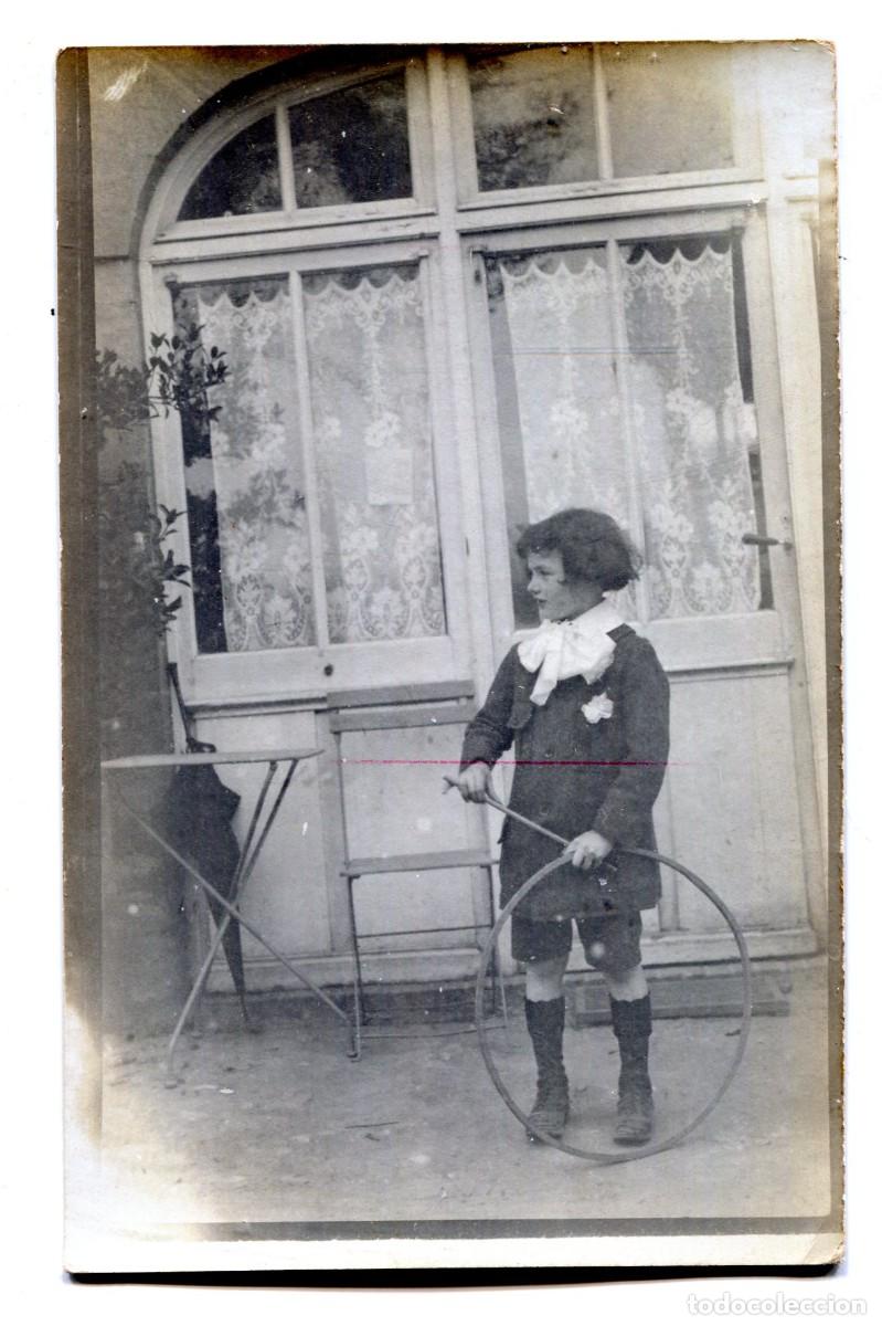 Fotograf&iacute;a antigua: Tarjeta fotogr&aacute;fica de un joven elegante jugando al aro frente a su casa hacia 1910