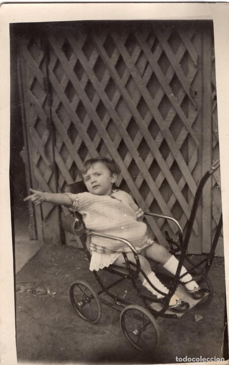 Fotograf&iacute;a antigua: Tarjeta fotogr&aacute;fica de una ni&ntilde;a peque&ntilde;a en su cochecito posando en el patio de su casa