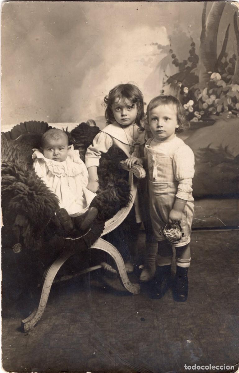 Fotograf&iacute;a antigua: Tarjeta fotogr&aacute;fica de dos ni&ntilde;os peque&ntilde;os elegantes con un beb&eacute; posando en un estudio fotogr&aacute;fico