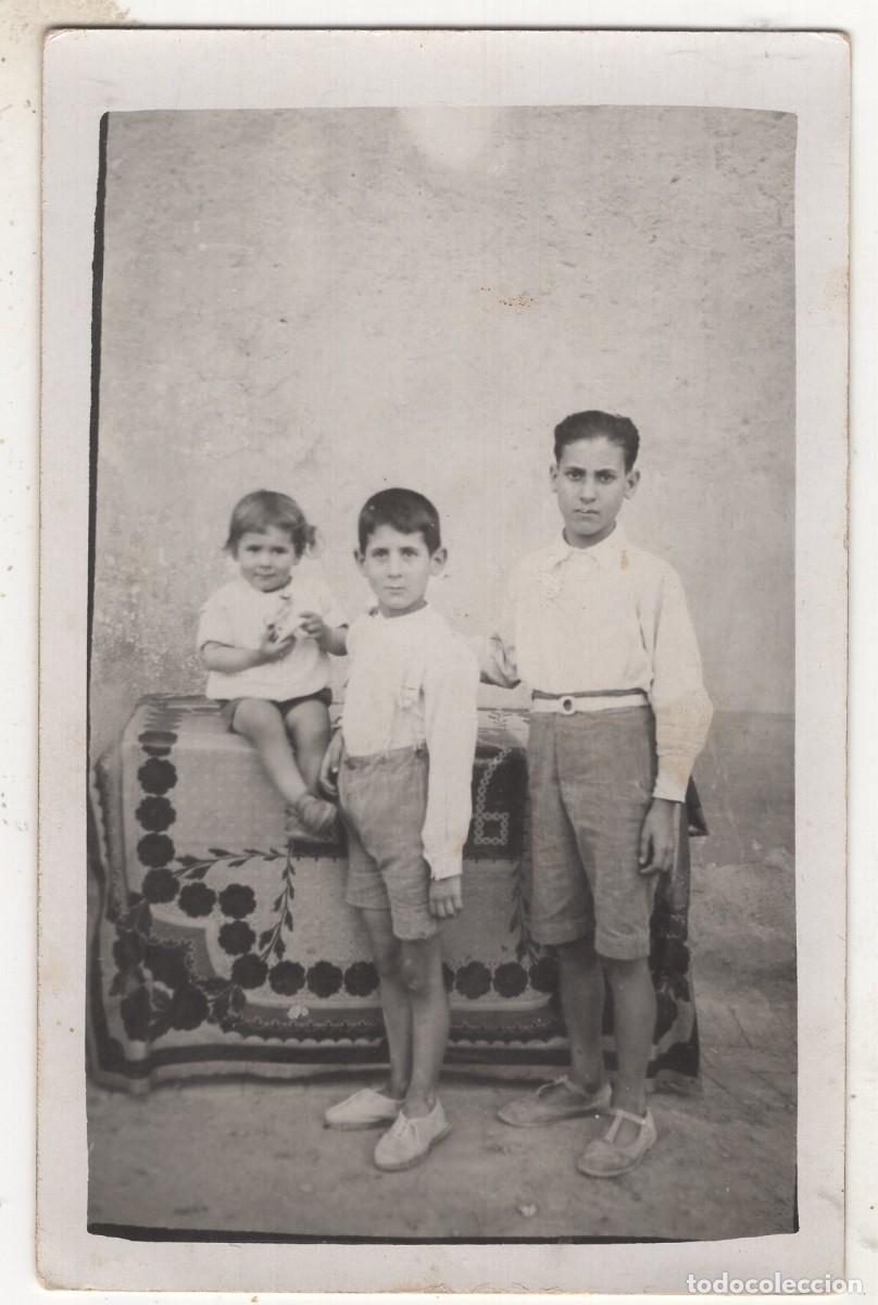 Fotograf&iacute;a antigua: Tarjeta fotogr&aacute;fica de dos j&oacute;venes con un ni&ntilde;o peque&ntilde;o posando en el patio de su casa.