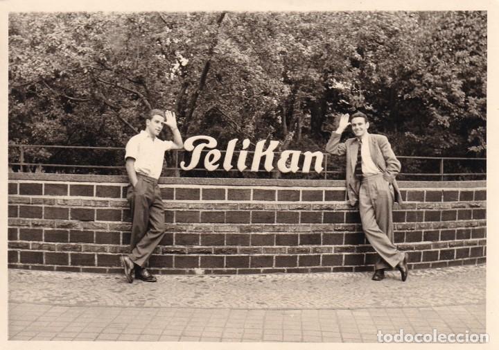 Fotograf&iacute;a antigua: Fotograf&iacute;a antigua de dos hombres junto a un letrero de Pelikan