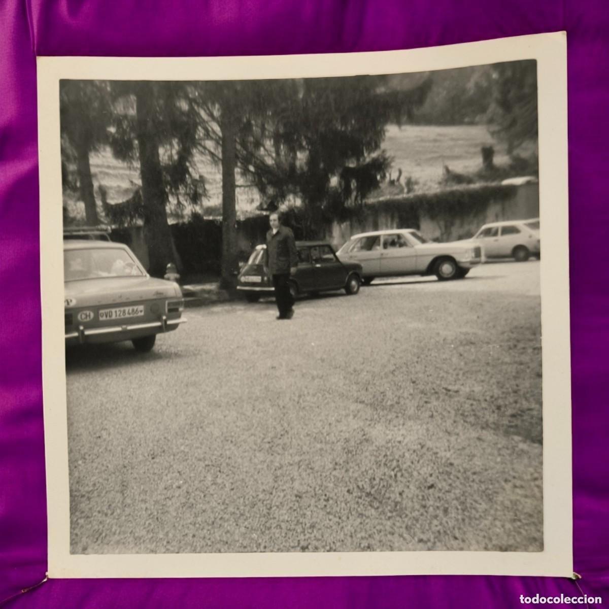 Fotografia antica: Fotograf&iacute;a Vintage En Blanco Y Negro &ndash; Aparcamiento Con Coches Cl&aacute;sicos Y Personaje Central A&ntilde;os 70