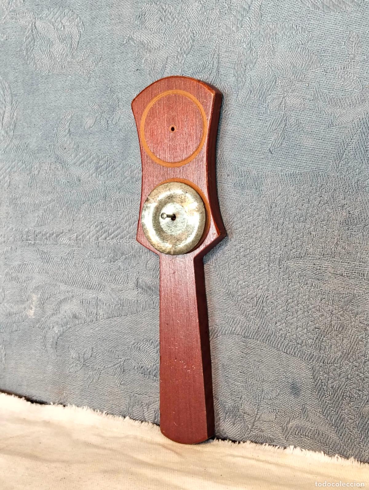 Instrumentos musicales: Utensilio de madera antiguo o vintage con pieza de metal y mango posiblemente instrumento pandereta