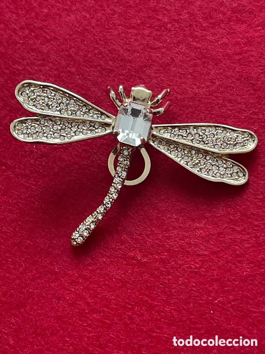 Gioielleria: Pendiente en forma de lib&eacute;lula en metal dorado y piedra central transparente.