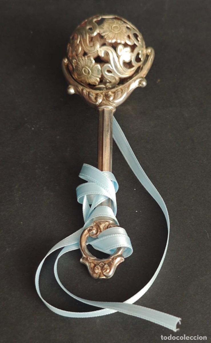 Joyeria: Elegante sonajero antiguo de plata con decoraci&oacute;n calada de motivos florales y mango ornamentado. Pi
