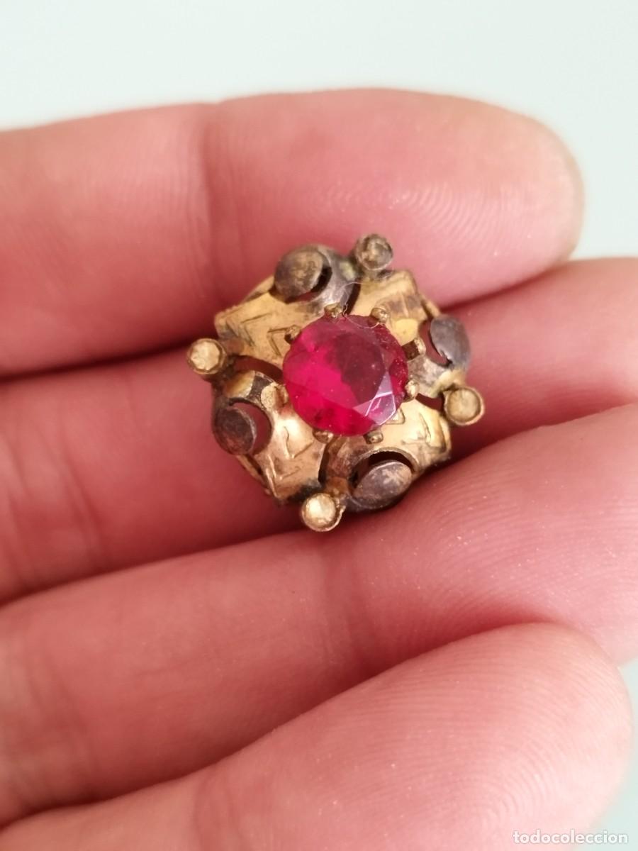 Joyeria: Antiguo pendiente met&aacute;lico intrincado con p&aacute;tina de envejecimiento y una piedra roja central tallada