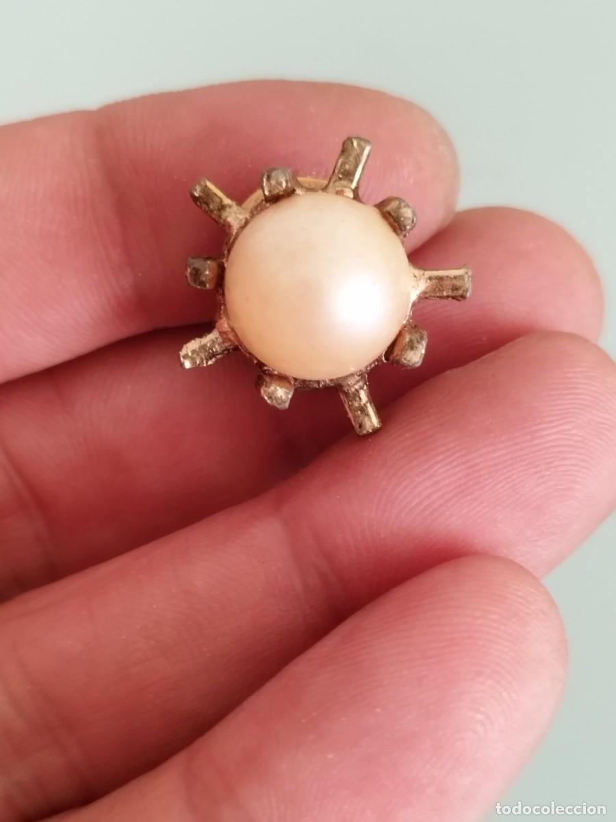 Joalharia: Antiguo pendiente con tipo perla engastada en una estructura de metal dorado.