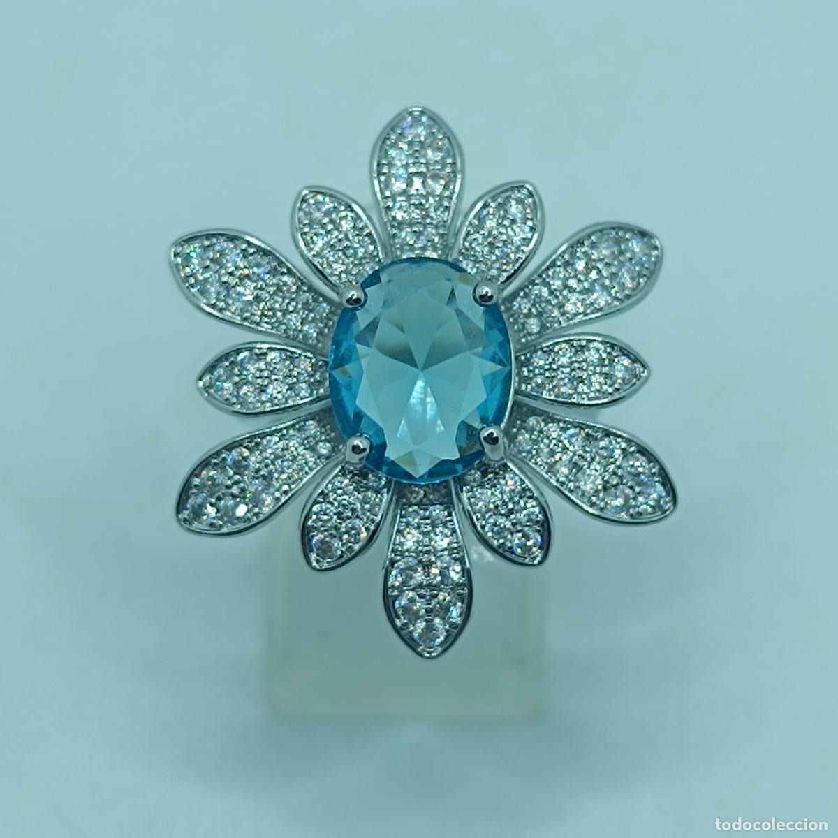 Joyeria: Maravilloso anillo de flor chapado en oro blanco de 18k, circonitas y aguamarina creada talla oval.