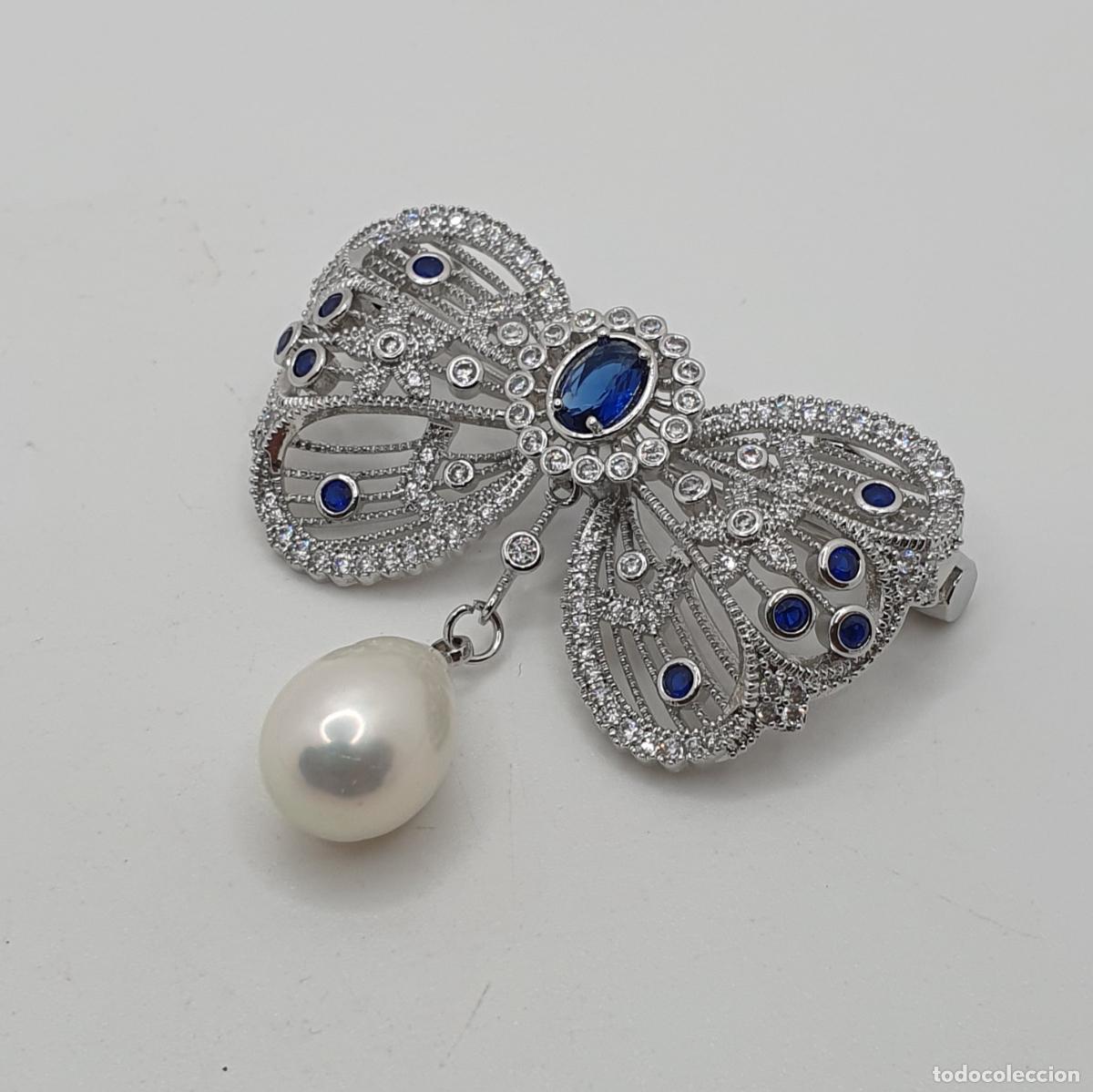 Joyeria: Exquisito broche de corte barroco chapado en oro blanco, circonitas, zafiros creados y perla natural