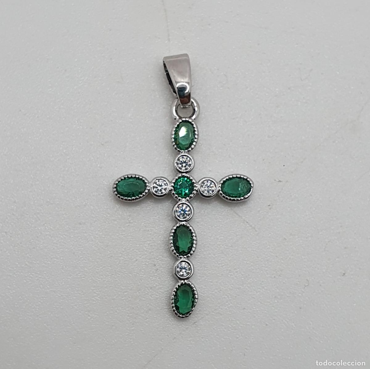 Joyeria: Elegante colgante de cruz chapada en oro blanco de 18k, circonitas y esmeraldas creadas talla oval.