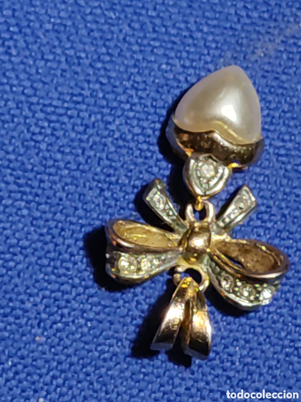 Joyeria: Colgante lazo dorado con coraz&oacute;n de perla simulada.