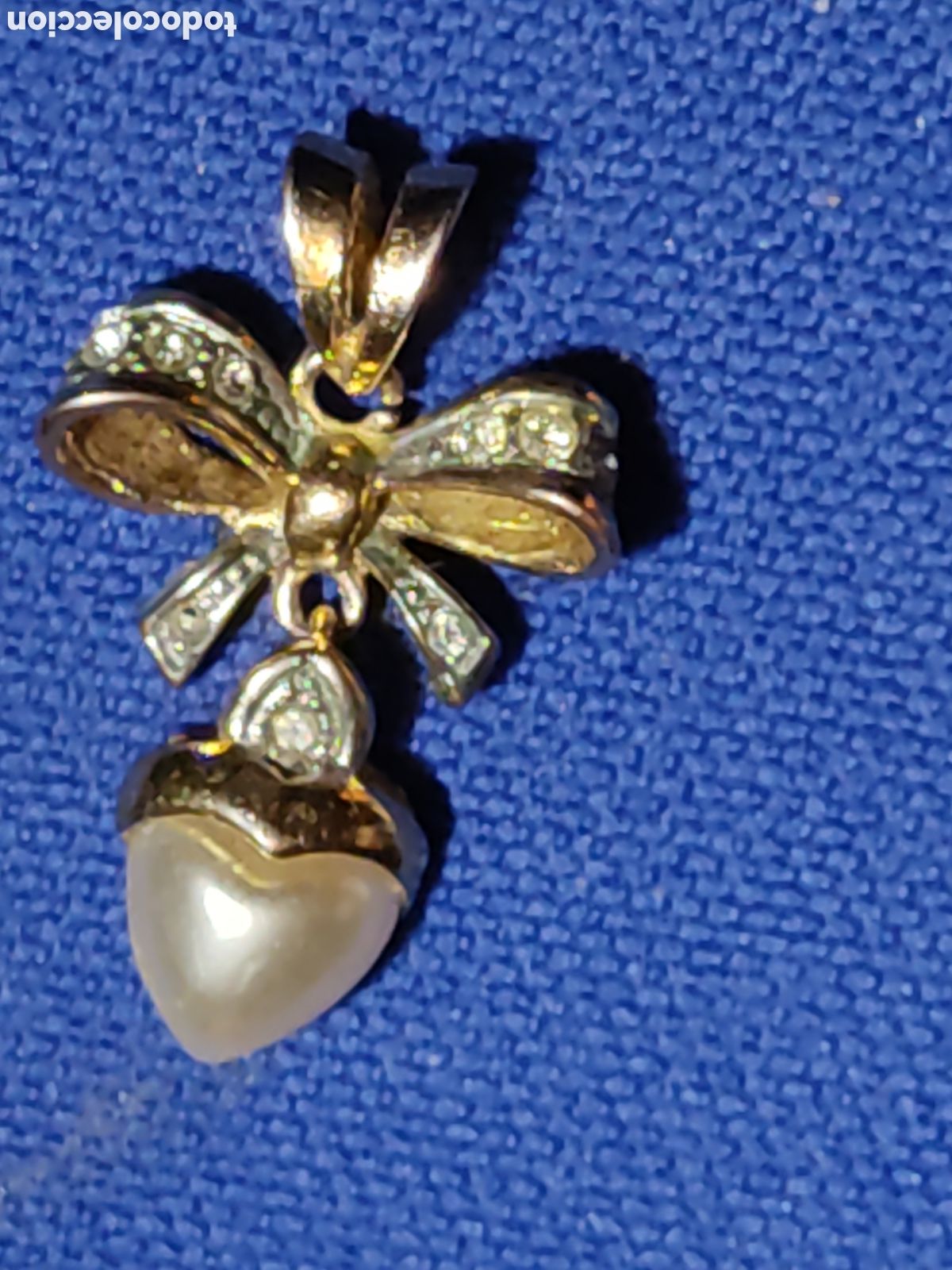 Joyeria: Colgante lazo dorado con coraz&oacute;n de perla simulada.