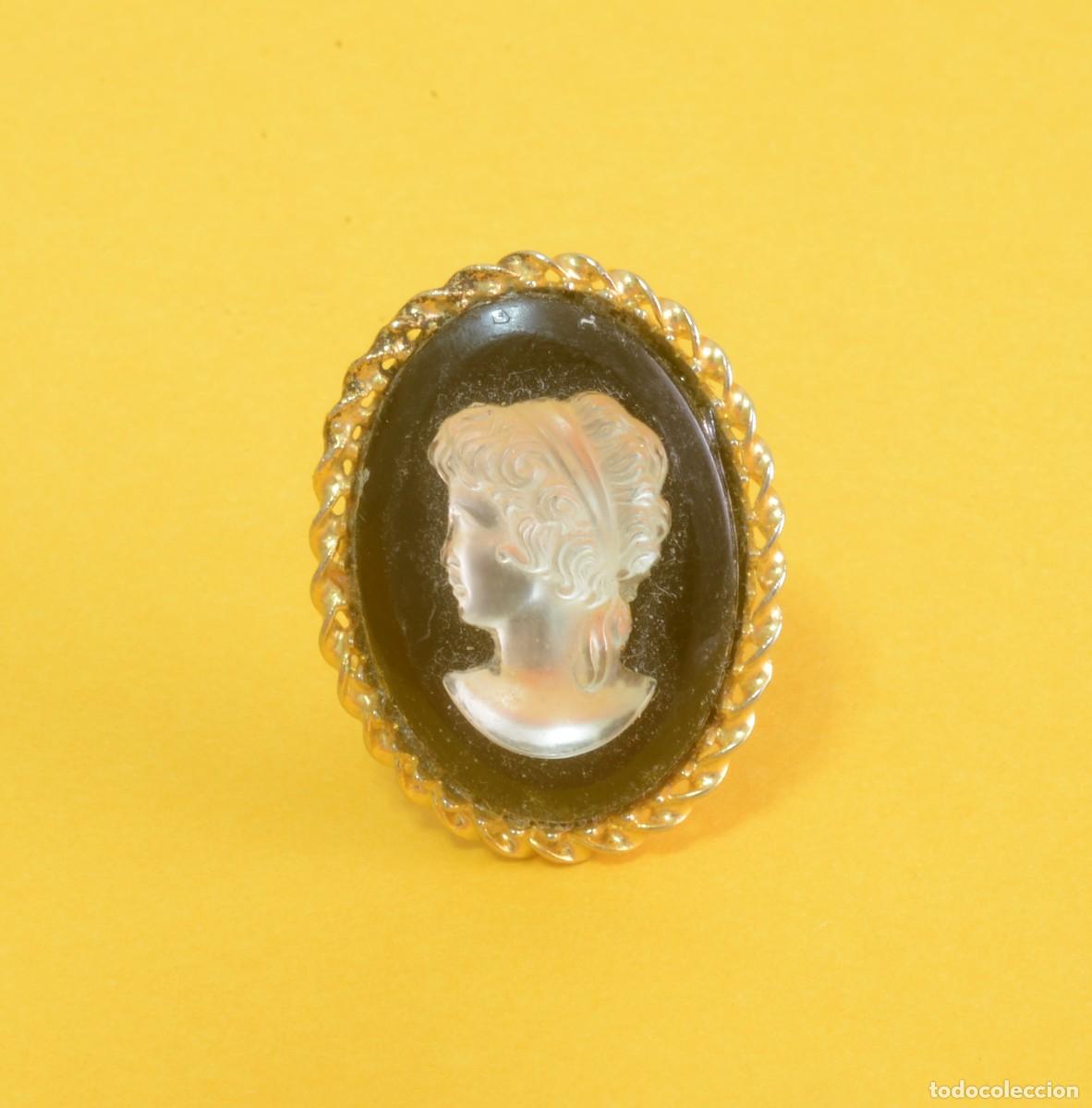 Joyeria: Broche vintage de camafeo perfil de mujer en relieve blanco sobre un fondo negro, engastado en marc