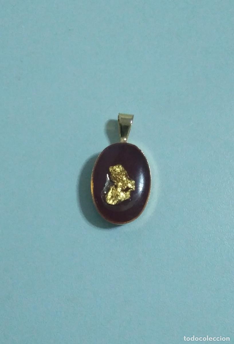 Joyeria: Colgante con lamina de oro sobre fondo rojo oscuro