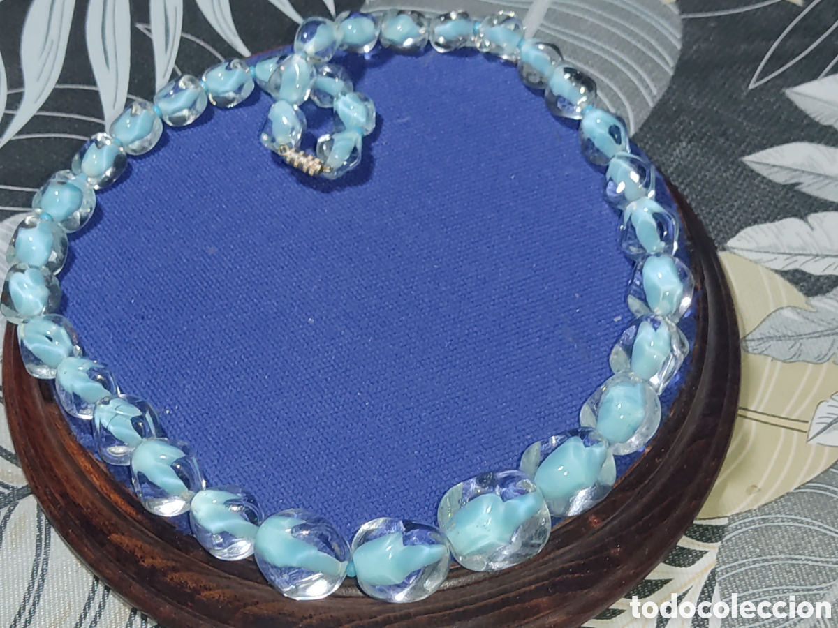 Joyeria: Collar de hermosas cuentas de cristal de Murano con fondo azul celeste.