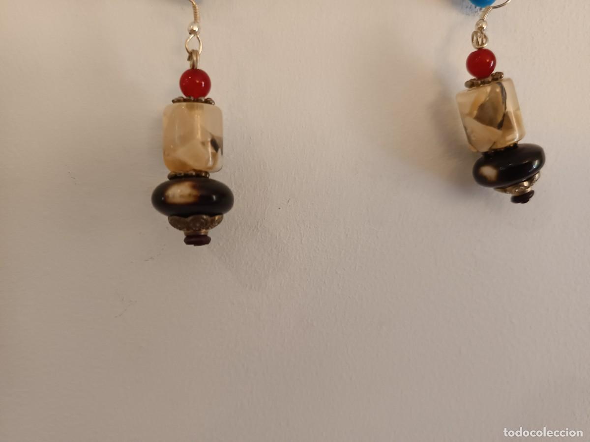 Joyeria: Pendientes colgantes artesanales que cuentan con cuentas de colores rojo y marr&oacute;n