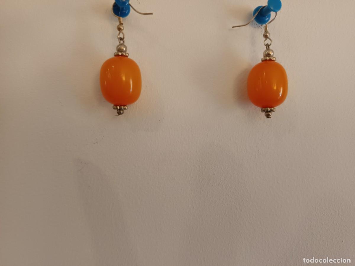 Joyeria: Pendientes largos hechos con cuentas de resina naranja y cuentas plateadas