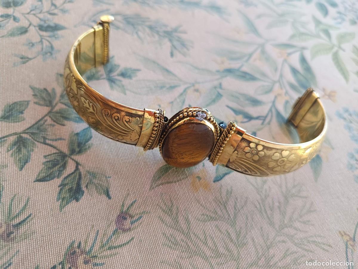Joyeria: Brazalete elaborado en lat&oacute;n dorado y cuenta con una gran piedra cabuj&oacute;n de ojo de tigre
