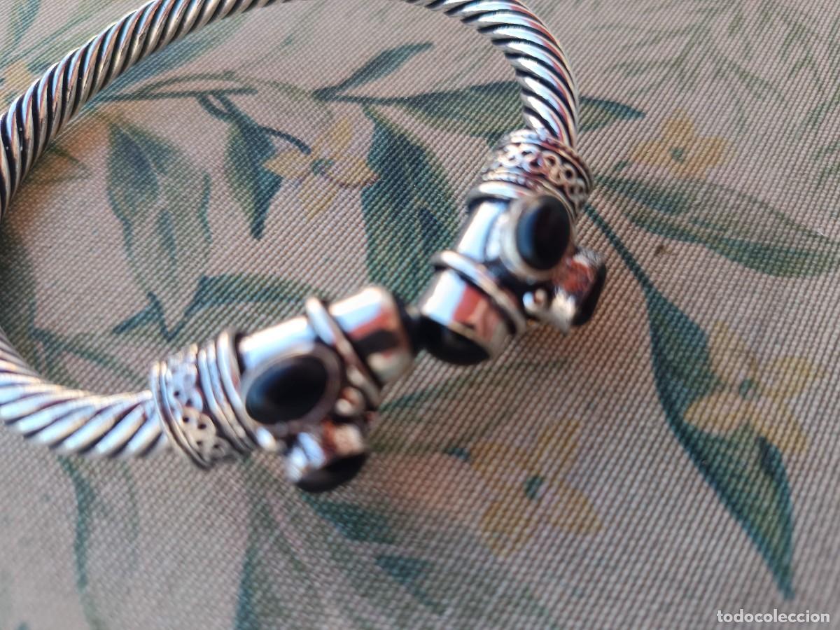 Joyeria: brazalete plateado de metal entrelazado y piedra en negro